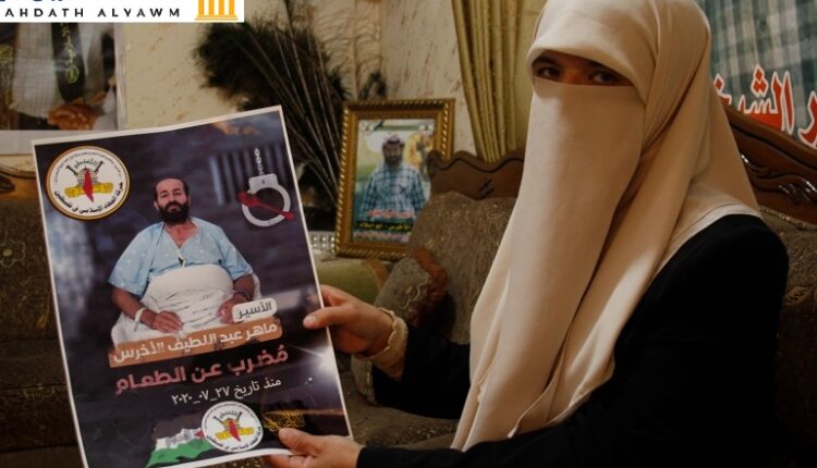 زوجة الأسير ماهر الأخرس تحمل صورته داخل منزلها