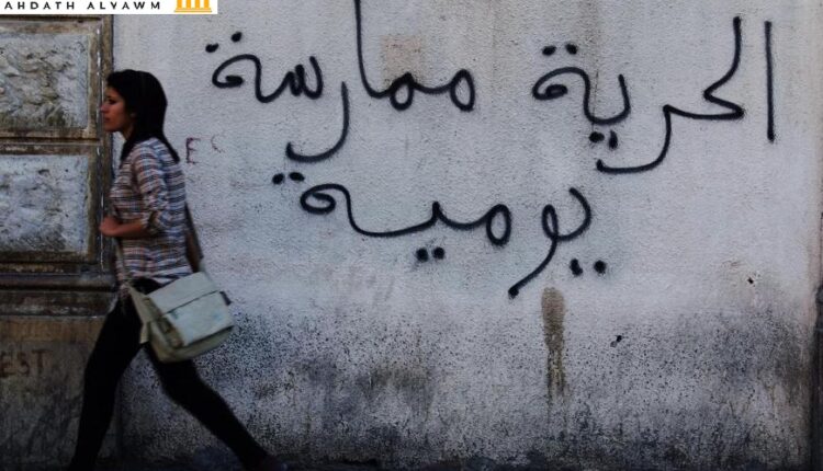 امرأة تونسية تسير أمام جدار كُتِبت عليه عبارة "الحرية ممارسة يومية" في العاصمة تونس