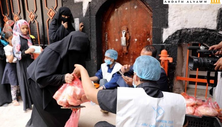 عامل يقدم حصة غذائية إلى امرأة في مطبخ خيري في صنعاء، اليمن