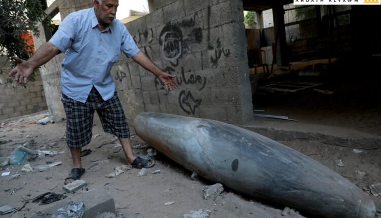 رجل فلسطيني ينظر إلى قنبلة غير منفجرة ألقتها طائرة حربية إسرائيلية من طراز F-16 على حي الرمال في مدينة غزة في 18 مايو 2021