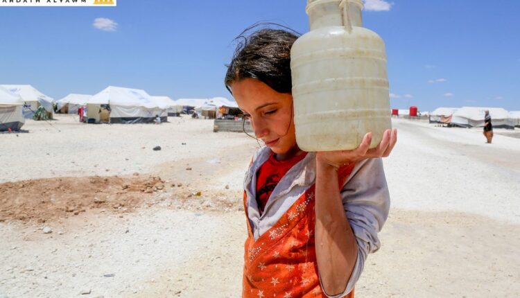 فتاة تحمل المياه في مخيم مؤقت في عين عيسى بسوريا.