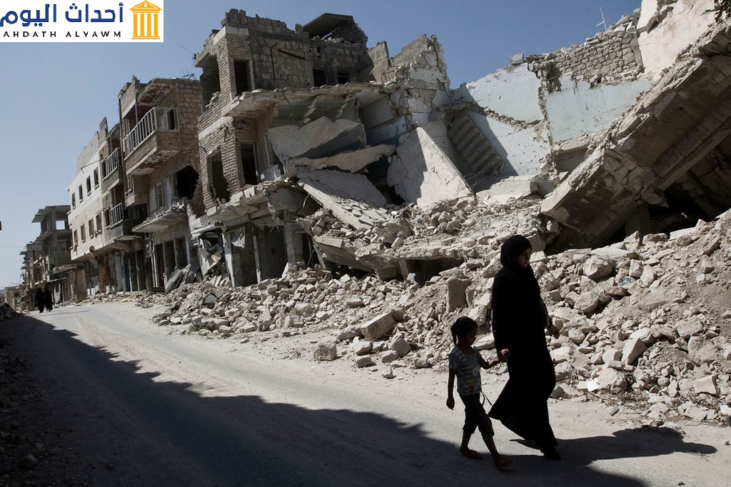 فتاة وامرأة يمشيان بالقرب من بنايات مدمرة في مدينة معرة النعمان بريف إدلب، سوريا
