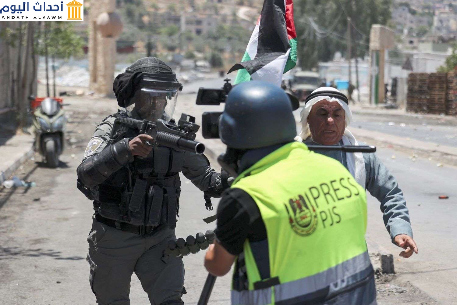 أحد عناصر قوات الأمن الإسرائيلية يحمل قاذفة غاز مسيل للدموع أمام صحفي، جنوب نابلس - الضفة الغربية المحتلة، 18 يونيو 2021 (عباس المومني/ وكالة الصحافة الفرنسية AFP)