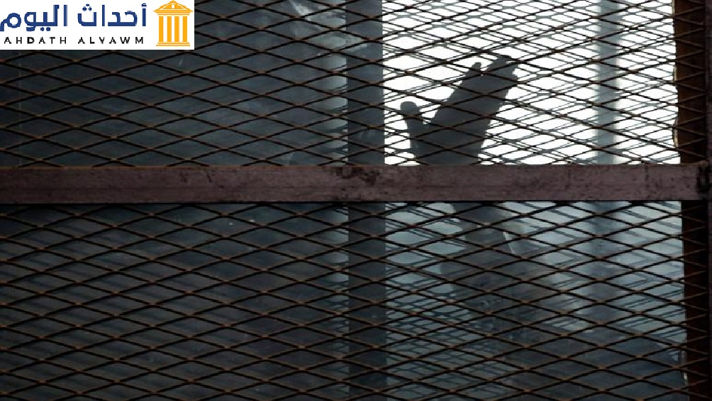صورة أرشيفية لأحد أعضاء جماعة الإخوان المسلمين يلوح بيده من داخل قفص المتهمين في قاعة محكمة بسجن طرة، جنوب القاهرة، 22 آب/أغسطس 2015