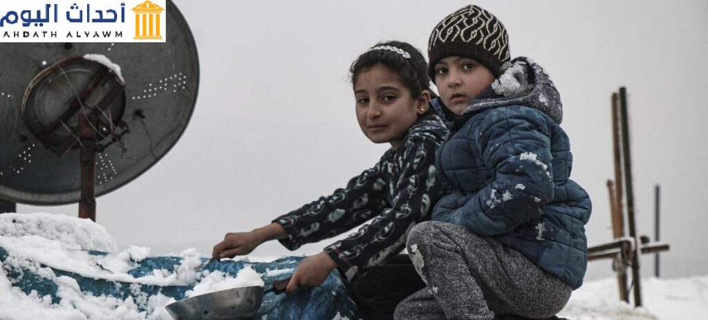 طفلان في مخيم كللي في إدلب في شمال غرب سوريا يحاولان إزالة الثلوج عن الخيمة