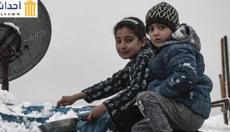 طفلان في مخيم كللي في إدلب في شمال غرب سوريا يحاولان إزالة الثلوج عن الخيمة
