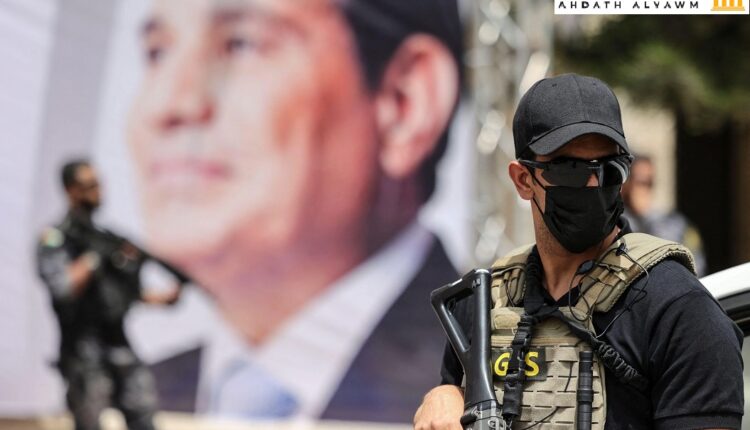 أحد عناصر المخابرات المصرية يقف قرب لافتة تُظهر الرئيس عبد الفتاح السيسي