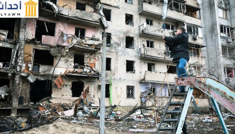 رجل يصور مبنى سكنيًا تعرض لأضرار جسيمة أثناء الصراع المتصاعد ، في كييف ، أوكرانيا