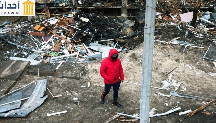 رجل يمشي أمام حفرة خلفها انفجار أثناء الصراع المتصاعد في كييف، أوكرانيا