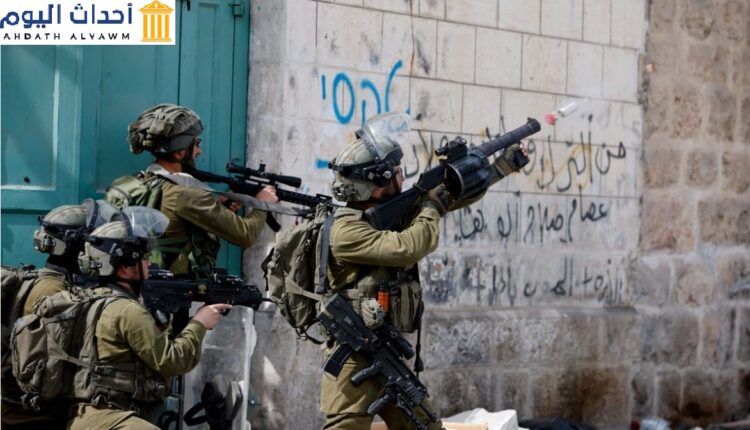 جندي إسرائيلي يستخدم سلاحًا تجاه متظاهرين فلسطينيين في مدينة الخليل بالضفة الغربية المحتلة