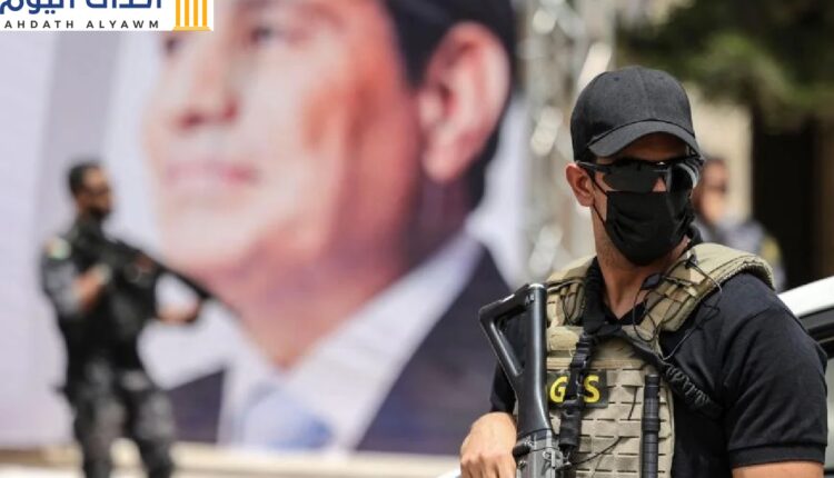 أحد عناصر المخابرات المصرية يقف قرب لافتة تُظهر الرئيس عبد الفتاح السيسي