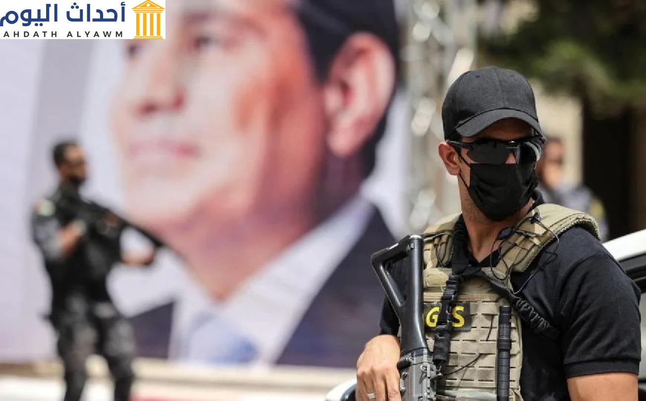 أحد عناصر المخابرات المصرية يقف قرب لافتة تُظهر الرئيس عبد الفتاح السيسي