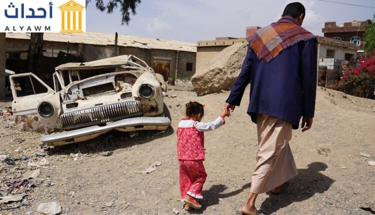 رجل يسير مع ابنته البالغة من العمر ثلاث سنوات في حي حارة المصنع الفقير في صنعاء، اليمن