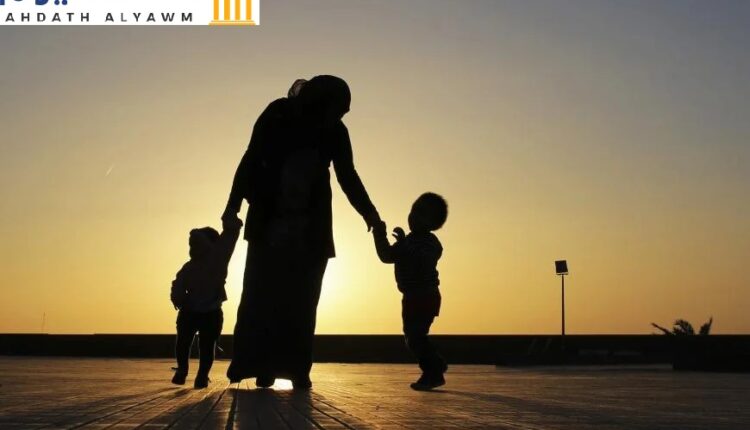 امرأة تمشي مع طفليها عند الغروب قرب شاطئ بنغازي