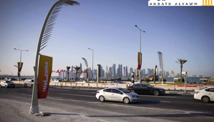 سيارات على الكورنيش ليلا مع أبراج الخليج الغربي في الدوحة في الخلفية