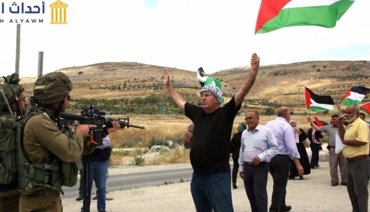 مجموعة من المواطنين الفلسطينيين يتظاهرون أمام أفراد الجيش الإسرائيلي احتجاجاً على قرار الذي أصدره وزير الأمن القومي الإسرائيلي الجديد "إيتمار بن غفير" الأحد، بمنع رفع العلم الفلسطيني ووصفه بالرمز “للإرهاب”