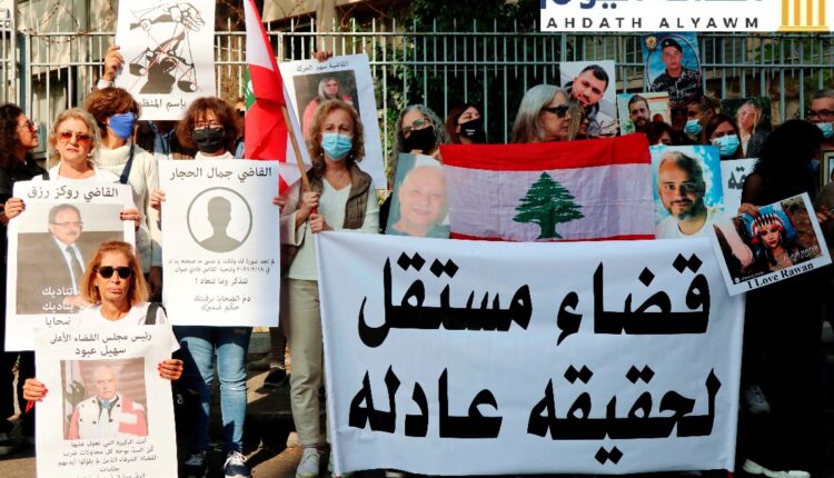 أهالي ضحايا إنفجار المرفأ يرفعون صور أحبائهم بالقرب من قصر العدل في بيروت في 25 نوفمبر/تشرين الثاني 2021. طالب الأقارب باستقلال القضاء لتحقيق العدالة