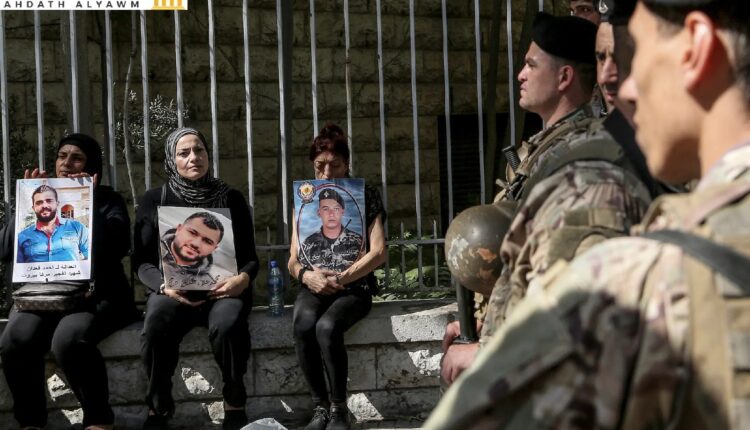 عائلات ضحايا انفجار مرفأ بيروت يحملون صورهم قرب جنود من الجيش اللبناني خلال مظاهرة أمام "قصر العدل" في بيروت