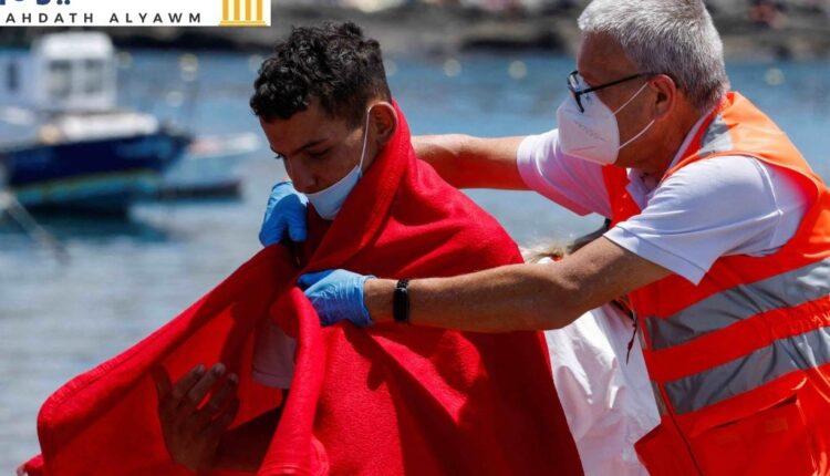 عضو في الصليب الأحمر يساعد مهاجرًا بعد نزوله من سفينة تابعة لخفر السواحل الإسبانية ، في ميناء أرغوينغوين ، بجزيرة غران كناريا ، إسبانيا