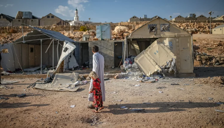 أشخاص يقيمون الأضرار الناجمة عن الهجوم بالذخائر العنقودية الذي شنه التحالف العسكري السوري الروسي على مخيم مرام للنازحين بالقرب من قرية كفر جالس في محافظة إدلب، شمال غرب سوريا