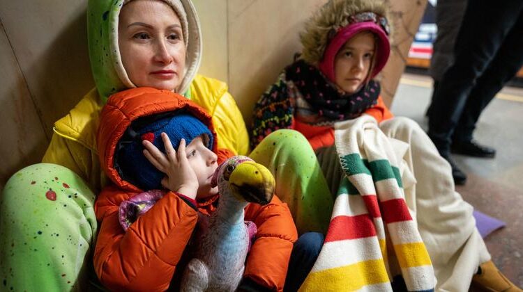 أم وابنتها وابنها يجلسون على الأرض في محطة مترو الأنفاق في كييف ليحتموا من القصف