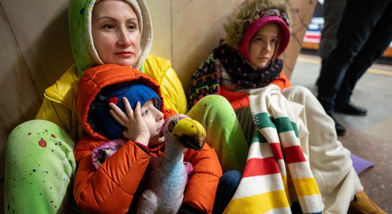 أم وابنتها وابنها يجلسون على الأرض في محطة مترو الأنفاق في كييف ليحتموا من القصف