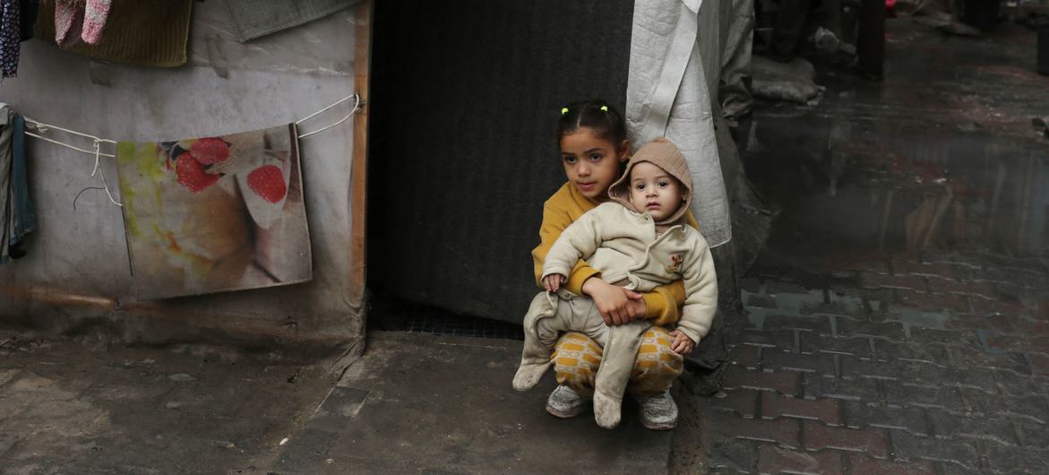 طفلة تحمل أخاها في ملجئ في غزة
